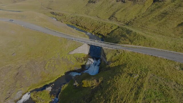 Road trip destination bridge over small waterfall in Iceland Hvalfjordur region, aerial drone