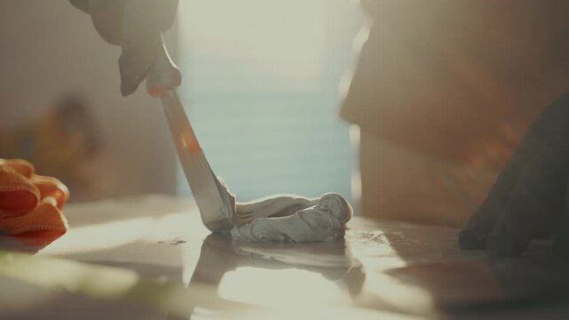 Pov of a worker mixing construction filler on flat surface using a putty knife. material preparation, renovation work, and professional surface repair techniques.