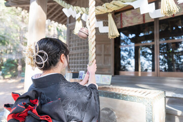 神社でお参りする着物姿の女性