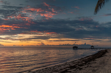 A stunning and colorful sunrise on a wooden pier on the beach in Cancun, Mexico