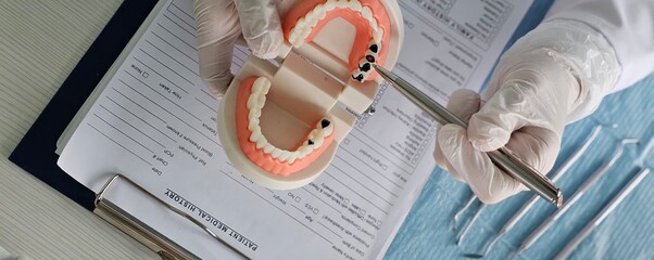 Dentist shows problem areas in teeth on artificial jaw