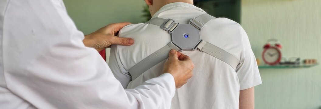 Doctor fits a back brace to a child in a clinic to support the spine and for rehabilitation