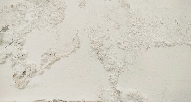 White wall paint background grumbling because it's been too long. Close up background of a white concrete cement wall that is cracked and the paint is peeling off. Old wall background wall with peelin
