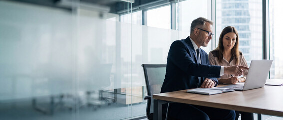 Two professional business people working together. Partners mature man and woman discussing project in office. Team leader explain trainee working process using tablet pc computer. Banner, copy space