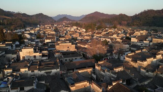 Xidi, China: Aerial forward drone footage of the famous Xidi ancient village with narrow street, temples and water steams near Huangshan in Anhui province in China at sunset