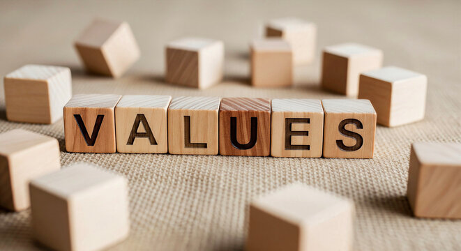 Wooden blocks spelling out the word VALUES surrounded by scattered cubes on a textured surface