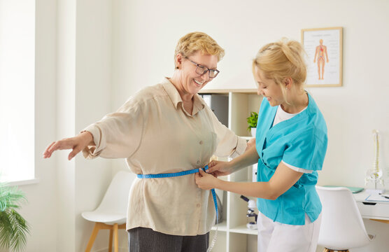 Nurse measuring waist of smiling senior woman with tape to check BMI on medical checkup in clinic. Body and belly measurements, patients weight control by doctor for health assessment