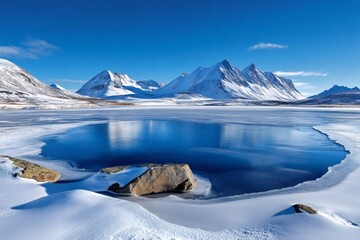 Frozen lake reflecting snow-capped mountains under blue sky