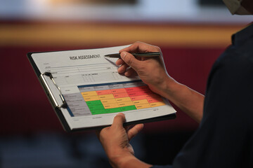 Focused worker holding document analyzing railway safety risk assessment matrix with pen...