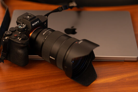  Bucharest Romania 16 January 2026. Sony Alpha A7 IV mirrorless camera next to a Mac laptop on a modern desk, professional photography and creative workspace setup.