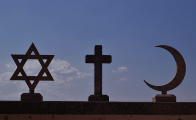 Hebrew star,  christ cross, half moon islam on roof of church in San Marino on dark heaven or sky.