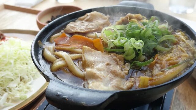 鍋焼きうどんの動画。うどんと豚肉と野菜を煮込んだ和食。クローズアップ。