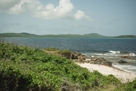 Man stands on rocky shoreline overlooking ocean in Vieques