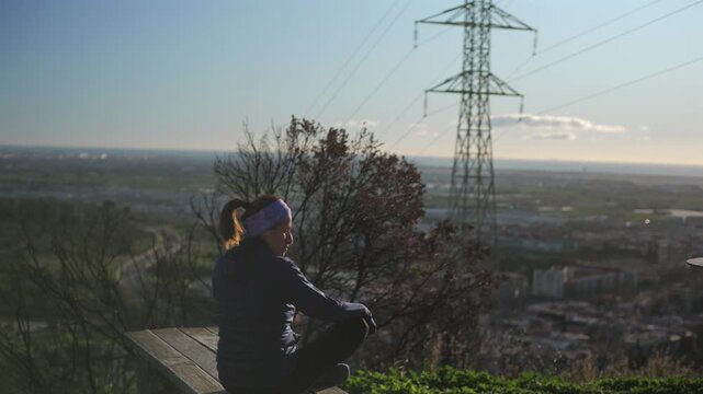 Woman rests at the mountain viewpoint and contemplates the city.
