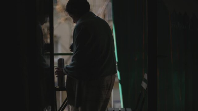 Woman drinks hot yerba mate on her balcony on a winter morning.