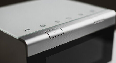 Close-up of modern electronic device control panel, featuring power button symbol on brushed aluminum and glass surface