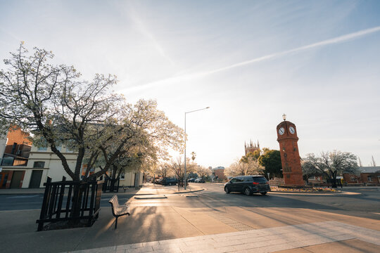 Car passing through rounadbout in rural Australian town with clock tower in spring
