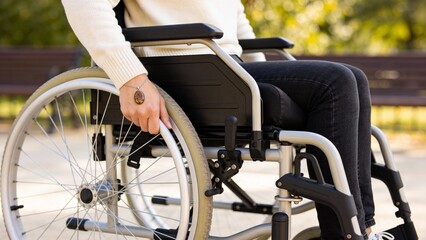 Person in wheelchair holding wheel while sitting outdoors in park  