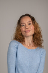 Vertical photo of a blonde woman with curls and a blue T-shirt