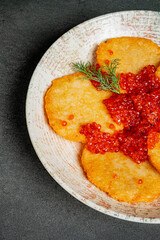 Savory golden pancakes artfully arranged and nestled under a rich layer of bright caviar