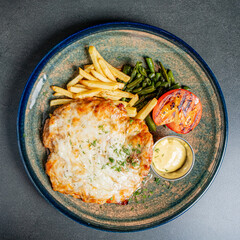 A delicious serving of cheesy chicken alongside golden fries and vibrant green beans