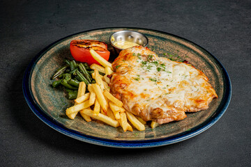 Savor the delightful combination of baked chicken, golden fries, and vibrant veggies on a plate