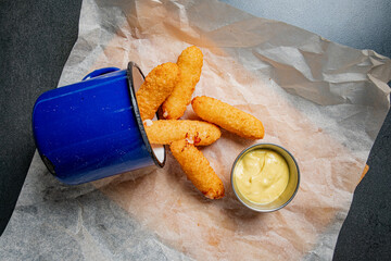 Golden-fried treats spill from a blue container, accompanied by a smooth, flavorful dip