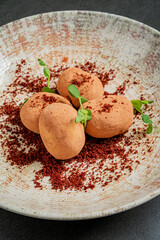 This dessert features creamy chocolate truffles coated in cocoa powder, artfully arranged