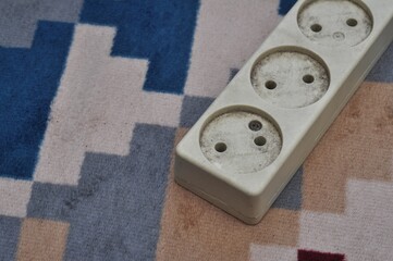 Old Electrical Power Strip on Patterned Carpet Indoor Background