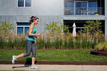 Woman, fitness and running outdoor in neighborhood with endurance training, exercise and wellness. Active, female person and runner in suburb for cardio challenge, workout and marathon preparation.