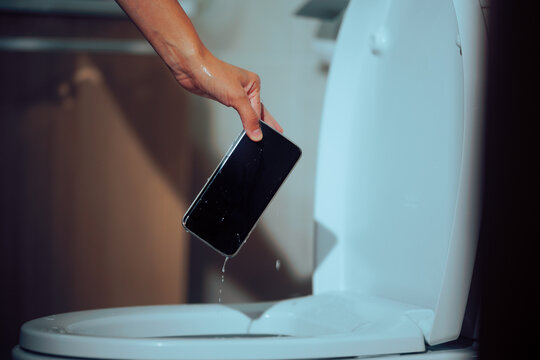 Person Takes Out Wet Smartphone from Toilet. Woman rescuing a wet cell phone after a bathroom accident 
