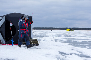 Ice fishing. Ice fisherman catching fish in a hole. Ice fishing for smelts in the Curonian Lagoon, Lithuania