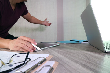 Business professional presenting data using tablet and laptop at desk