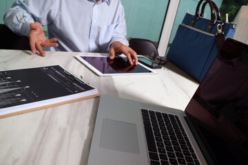 Business meeting with laptop, tablet, and financial documents on desk