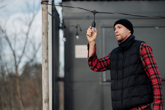 Man adjusts outdoor lights for a gathering in a backyard