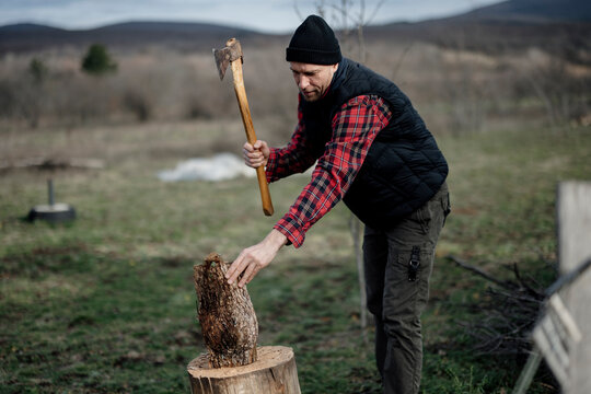 Man chops wood with an axe in a field