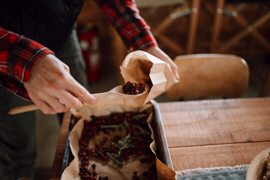Person uses a wooden spoon to scoop dried herbs and spices