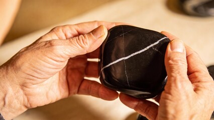 Person holding a black stone with white markings in their hands  