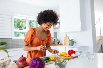 African american woman slicing mushrooms on cutting board at kitchen island