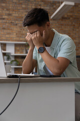 Silver laptop sitting open on desk in office, with coffee mug, smartphone, charging cable