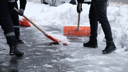 Municipal workers are cleaning the sidewalks blocked by snow. snow removal workers with snow shovels © MahmutSonmez