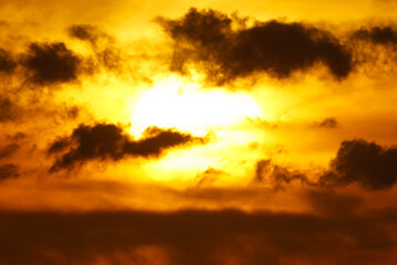 A sun is in the sky with clouds in the background