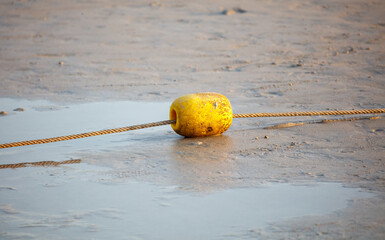 A yellow buoy is on the beach