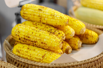A basket of yellow corn with some of them being burnt