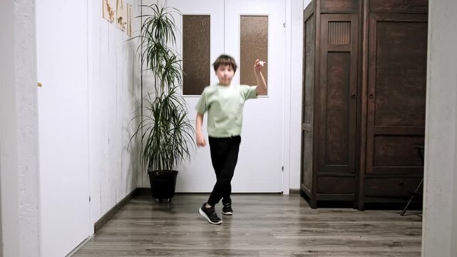 A schoolboy practices a Cris cross movement from a breakdancing lesson at home. Dancing hobby. A boy jumps up and crosses his legs. Athletic 9 year old child. Sports warm-up. High quality 4K footage.
