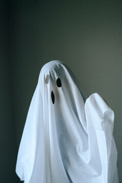 Child fooling around in ghost costume for Halloween indoors