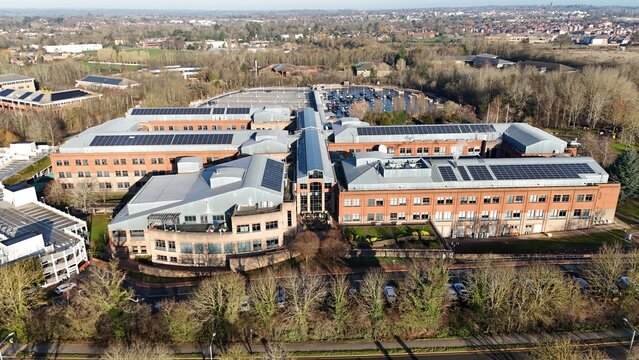 Aerial view of modern architecture adorned with solar panels amidst a winter landscape, its brick contrasting against the bare trees, Royal Leamington Spa, England, United Kingdom.