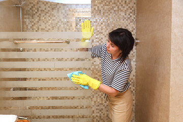 A housewife washes glass a shower stall.