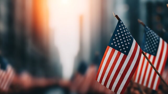 A close-up of multiple American flags waving in the breeze, set against a blurred urban backdrop, evoking a sense of patriotism and unity.
