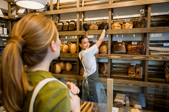 Bakery employee serving fresh bread to client at the counter